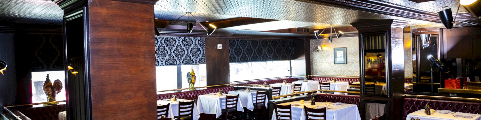 An elegantly furnished restaurant interior with wooden accents and white tablecloths, prepared for guests.