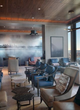 A modern lounge with plush seating, large windows offering a sea view, a wall mural, and cozy lighting.